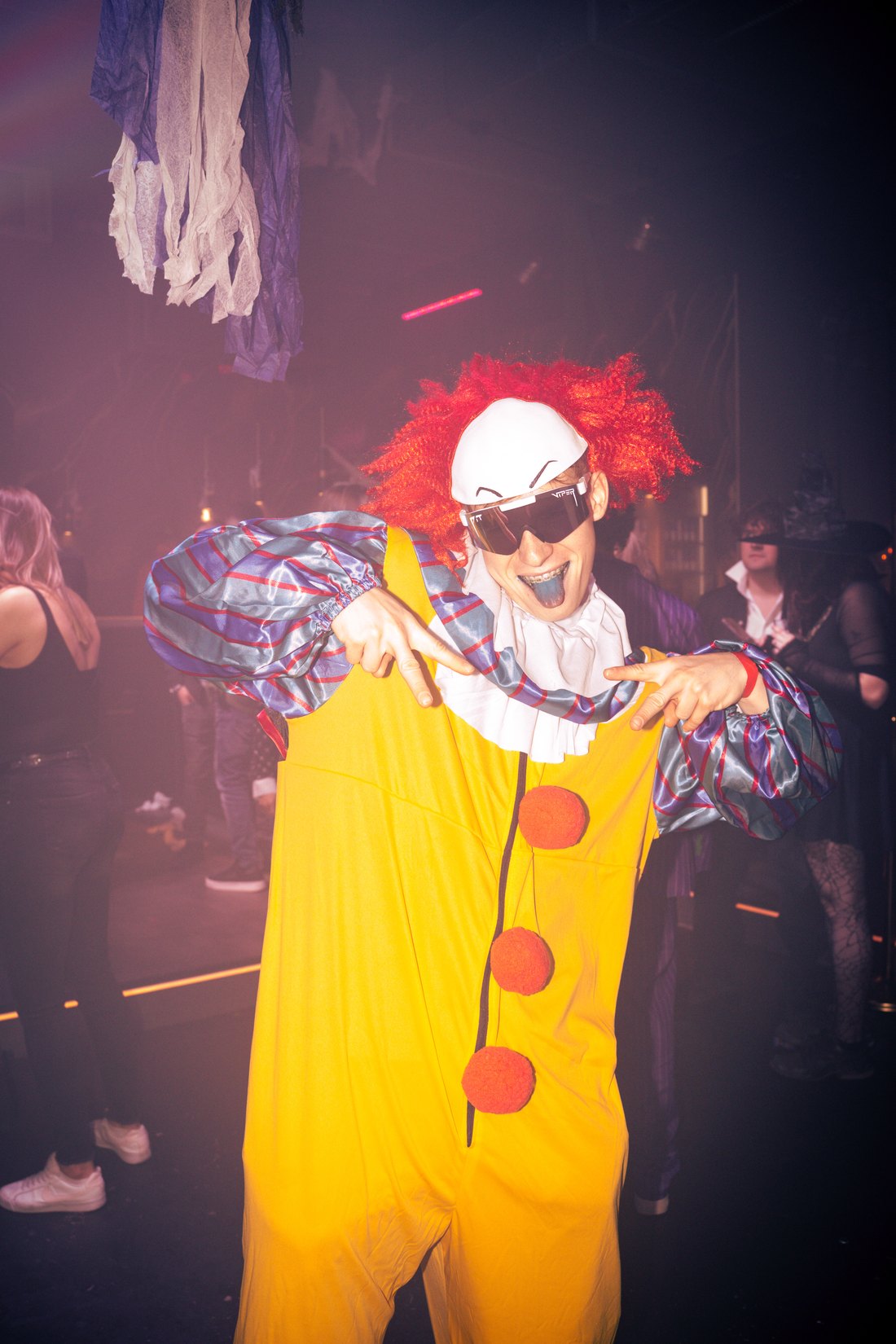 Gast im Clownskostüm mit Sonnenbrille auf einer Halloween-Party – PromoFlicks