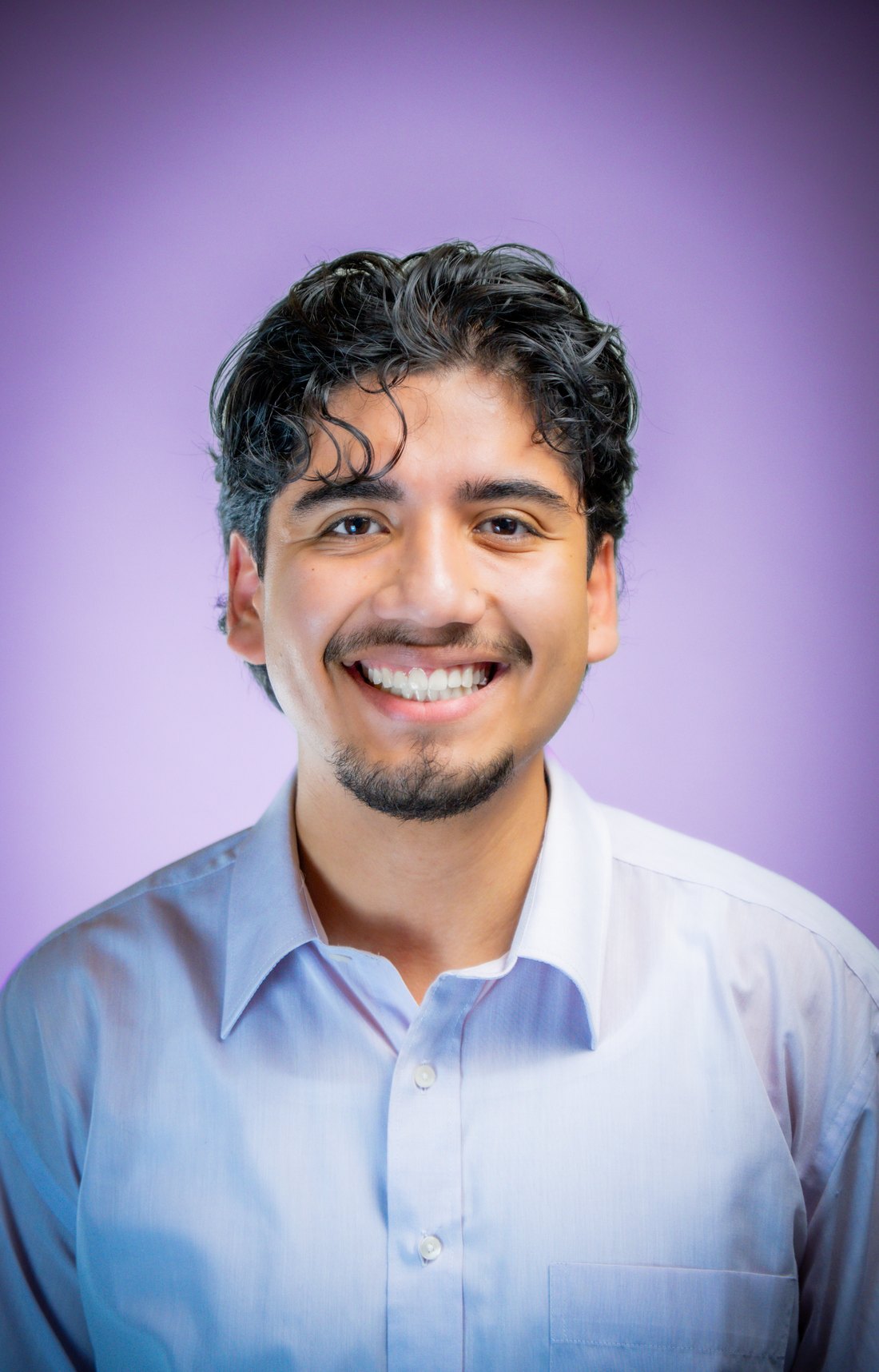 Business Portrait eines lachenden jungen Mannes vor violettem Hintergrund – PromoFlicks